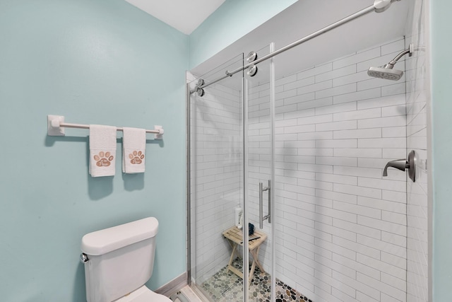 bathroom featuring a shower with shower door and toilet