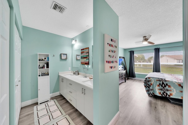 bathroom featuring ceiling fan, hardwood / wood-style floors, vanity, and a textured ceiling