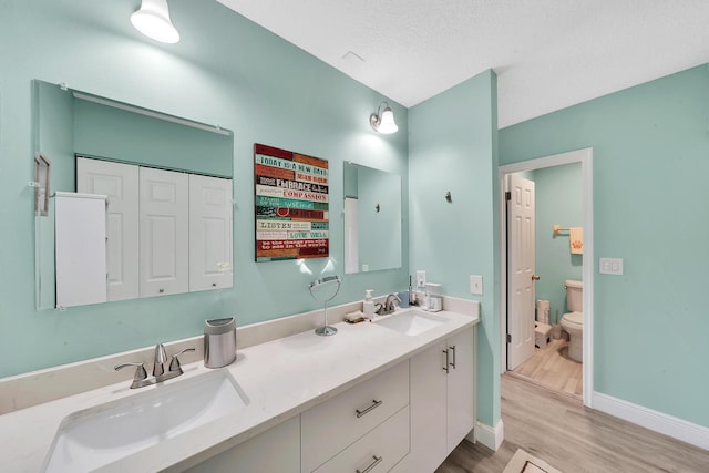 bathroom featuring toilet, vanity, a textured ceiling, and hardwood / wood-style floors