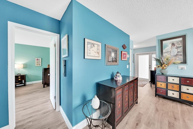 corridor featuring a textured ceiling, light hardwood / wood-style flooring, and french doors