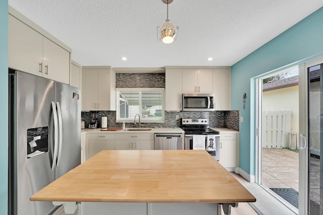 kitchen featuring hanging light fixtures, sink, stainless steel appliances, and a textured ceiling