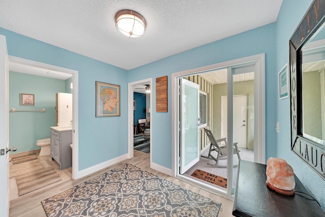 hallway with a textured ceiling and light hardwood / wood-style floors