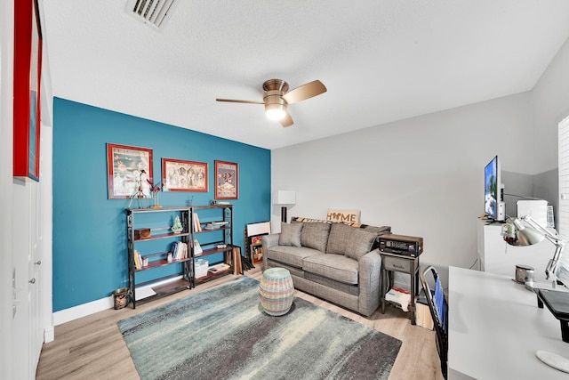 living room featuring a textured ceiling, ceiling fan, and light hardwood / wood-style floors