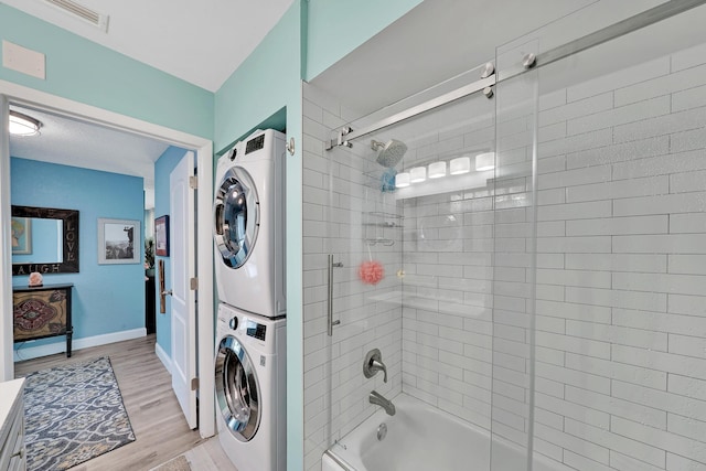 bathroom featuring tiled shower / bath combo, stacked washer / dryer, and hardwood / wood-style flooring