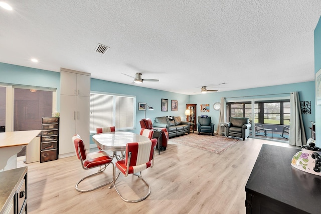 dining area with ceiling fan, a textured ceiling, and light hardwood / wood-style flooring