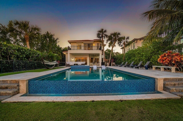 pool at dusk featuring a patio area