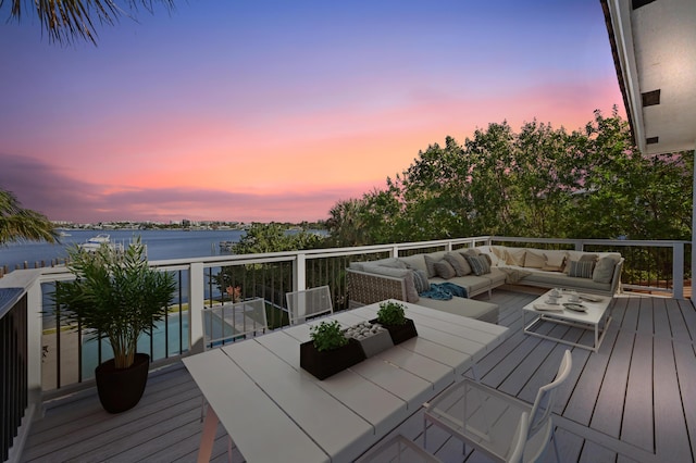 deck at dusk with a water view and an outdoor hangout area