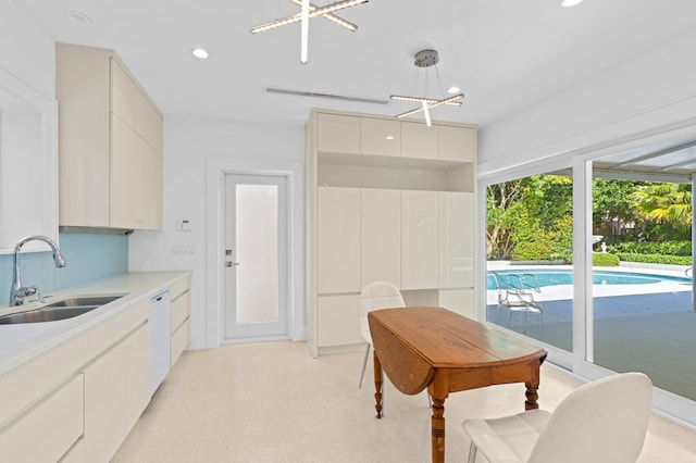 kitchen with sink, dishwasher, hanging light fixtures, and white cabinets