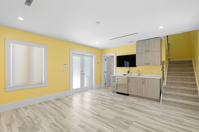 kitchen featuring dishwashing machine, light brown cabinets, light hardwood / wood-style flooring, and french doors