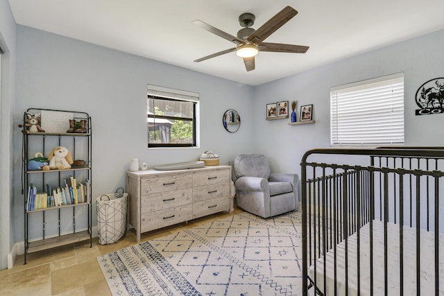 bedroom featuring ceiling fan and a crib