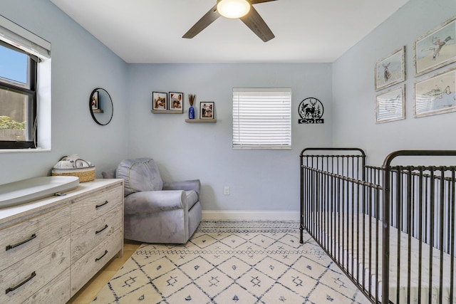 bedroom featuring a crib, multiple windows, and ceiling fan