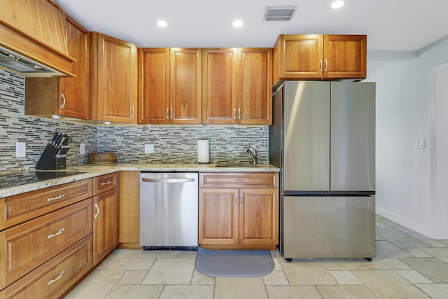 kitchen with light stone countertops, backsplash, custom exhaust hood, stainless steel appliances, and sink