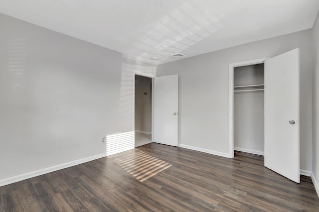 unfurnished bedroom with a closet and dark wood-type flooring