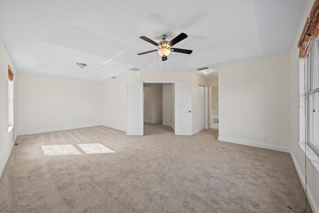 unfurnished bedroom with ceiling fan, light carpet, and a raised ceiling