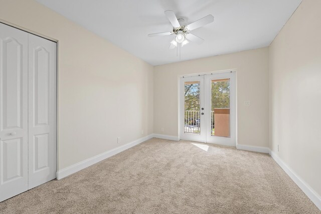 carpeted spare room with ceiling fan and french doors