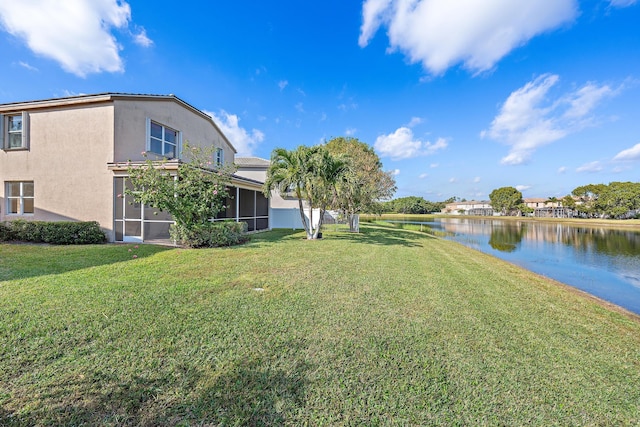 view of yard featuring a sunroom and a water view