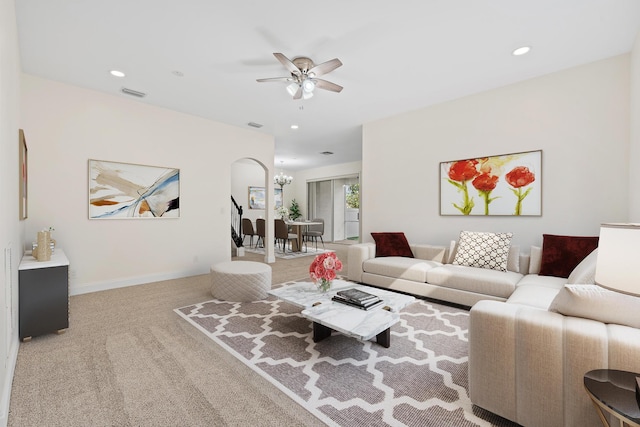 carpeted living room with ceiling fan with notable chandelier