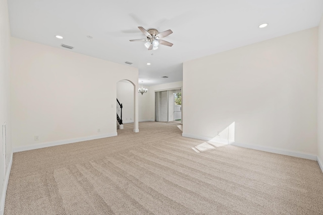 carpeted empty room with ceiling fan with notable chandelier