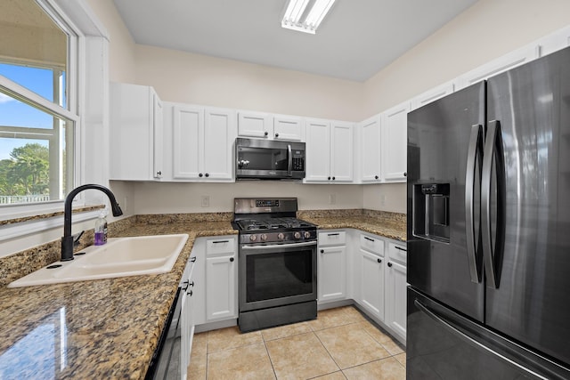 kitchen with stainless steel appliances, dark stone countertops, white cabinets, and sink