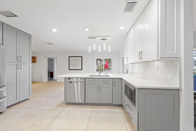 kitchen featuring kitchen peninsula, gray cabinets, stainless steel appliances, backsplash, and sink