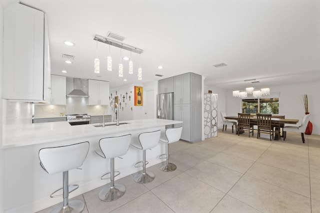 kitchen featuring appliances with stainless steel finishes, wall chimney exhaust hood, hanging light fixtures, and sink