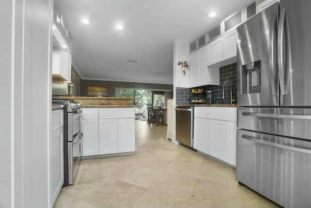 kitchen with decorative backsplash, white cabinets, appliances with stainless steel finishes, and a sink