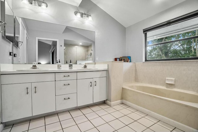 bathroom with vaulted ceiling, a bathtub, tile patterned floors, and vanity