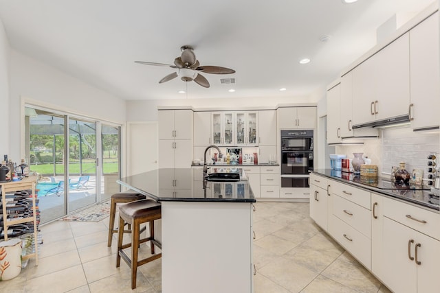 kitchen with a center island with sink, white cabinetry, black appliances, and sink