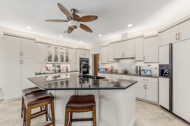 kitchen with a kitchen island with sink, black double oven, white cabinets, and white fridge with ice dispenser