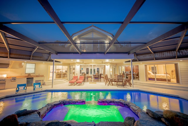 view of pool with an outdoor kitchen, glass enclosure, and a patio area