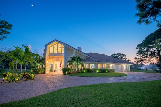 view of front of home with french doors, a garage, and a lawn