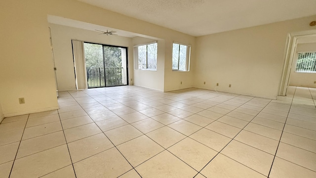 unfurnished room featuring a textured ceiling, light tile patterned floors, and ceiling fan