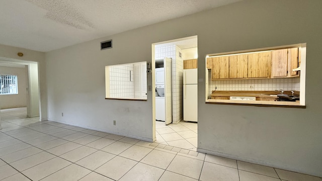 kitchen with sink, white refrigerator, backsplash, light tile patterned flooring, and a textured ceiling