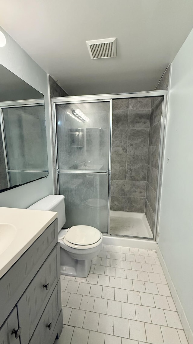 bathroom with toilet, tile patterned flooring, a shower with shower door, and vanity