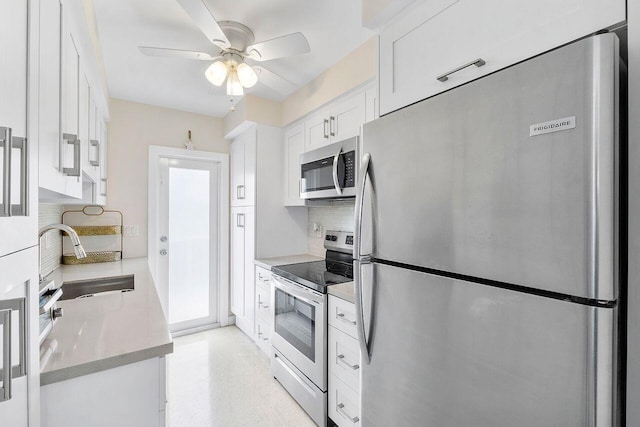 kitchen with tasteful backsplash, sink, white cabinets, ceiling fan, and stainless steel appliances