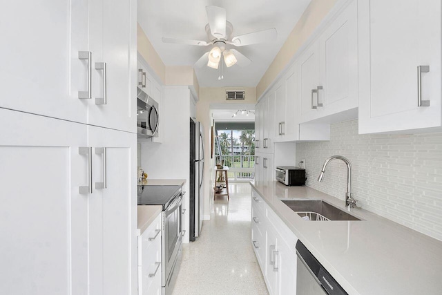 kitchen with sink, ceiling fan, white cabinetry, backsplash, and stainless steel appliances