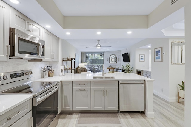 kitchen featuring gray cabinetry, ceiling fan, sink, stainless steel appliances, and kitchen peninsula