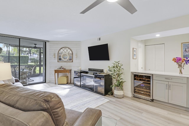 living room with wine cooler, ceiling fan, floor to ceiling windows, and light hardwood / wood-style floors