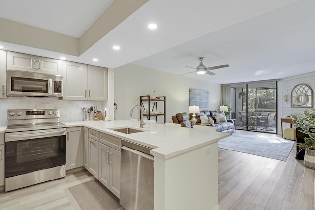 kitchen featuring sink, ceiling fan, appliances with stainless steel finishes, light hardwood / wood-style floors, and kitchen peninsula