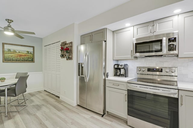 kitchen featuring appliances with stainless steel finishes, tasteful backsplash, gray cabinetry, ceiling fan, and light hardwood / wood-style flooring