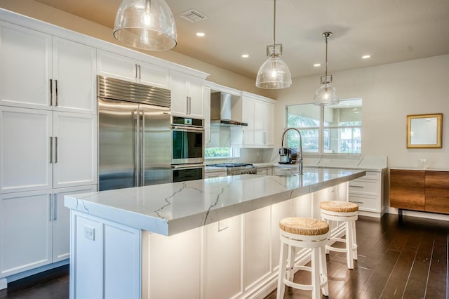 kitchen featuring a large island with sink, sink, stainless steel appliances, and white cabinetry