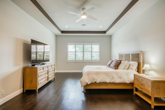 bedroom with ceiling fan, multiple windows, a tray ceiling, and dark hardwood / wood-style floors