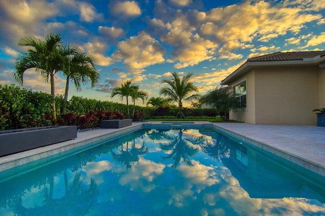 pool at dusk featuring a patio area