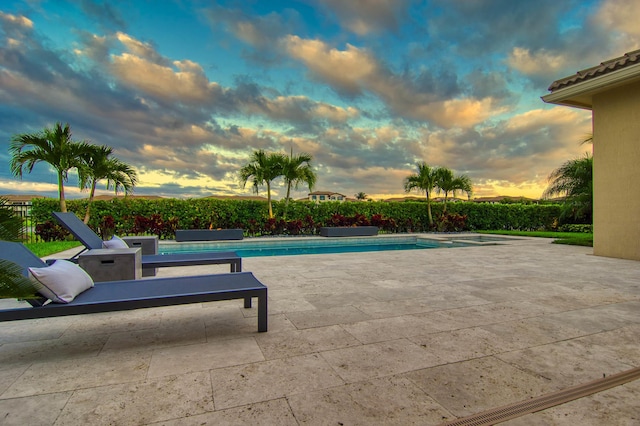 pool at dusk with a patio area