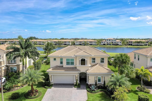 mediterranean / spanish-style house featuring a garage, a front lawn, and a water view