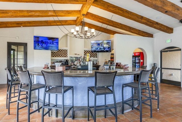 kitchen featuring kitchen peninsula, a breakfast bar area, decorative light fixtures, a chandelier, and beamed ceiling