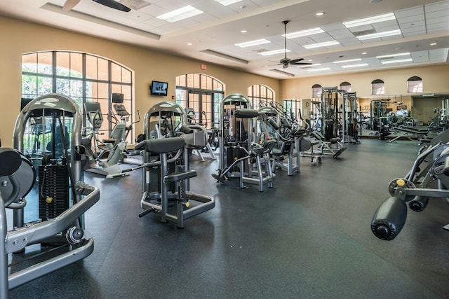 gym featuring ceiling fan, a paneled ceiling, and a towering ceiling