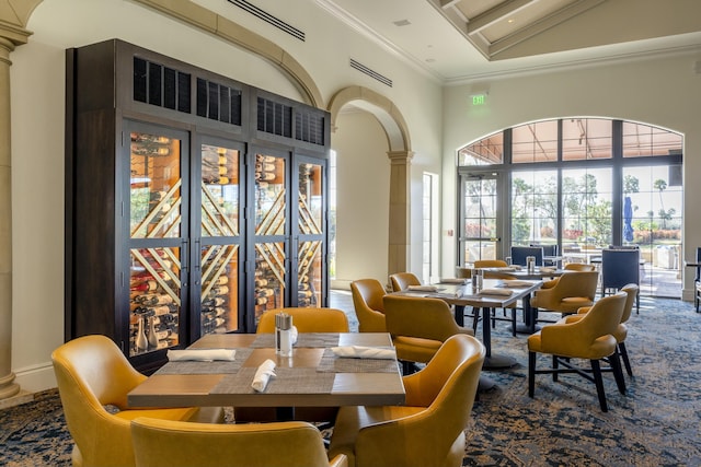 dining space with high vaulted ceiling, ornamental molding, and decorative columns