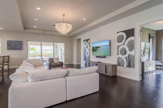 living room with a chandelier, dark hardwood / wood-style flooring, and a raised ceiling