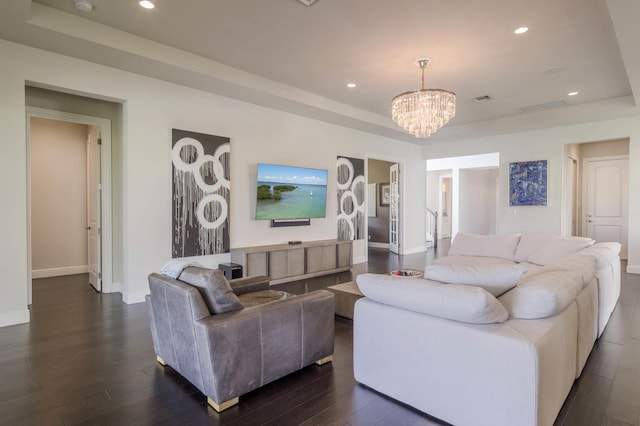 living room with dark hardwood / wood-style floors, a chandelier, and a raised ceiling